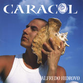 A man holding a conch shell in front of the ocean.