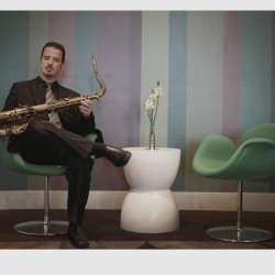 A man sitting on a chair holding a saxophone.