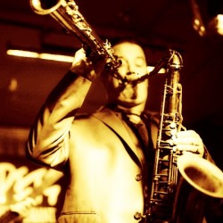 A man playing the saxophone in front of other people.