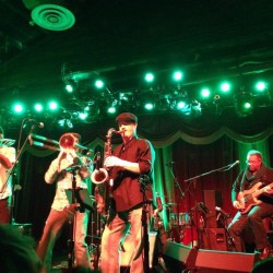 A band playing on stage under green lights.