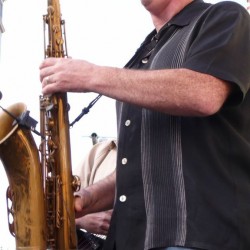 A man playing the saxophone in front of other people.