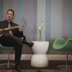 A man sitting on a chair holding a saxophone.